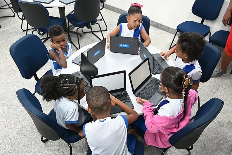 Estudantes usando notebooks em volta de uma mesa redonda